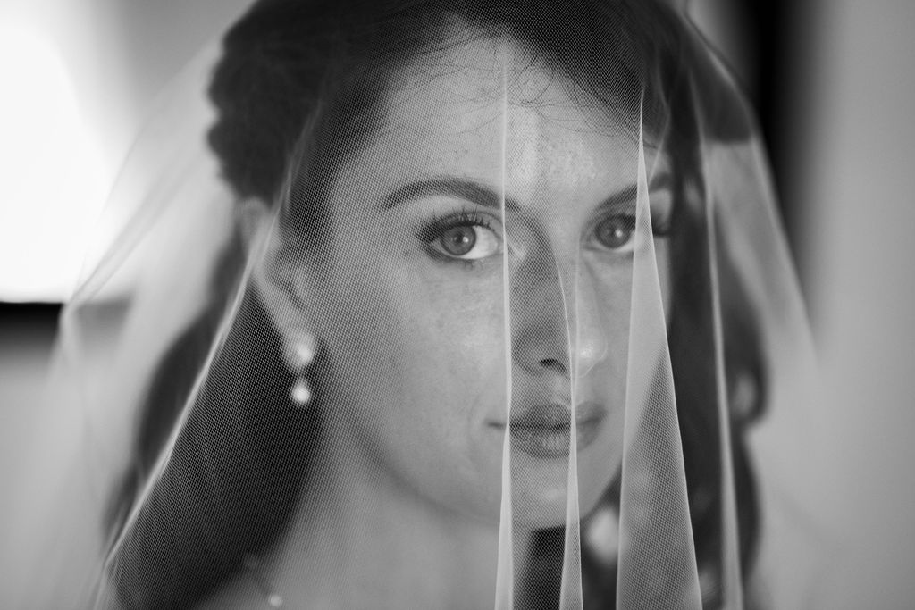 Bride looking straight into the camera through her veil, black and white