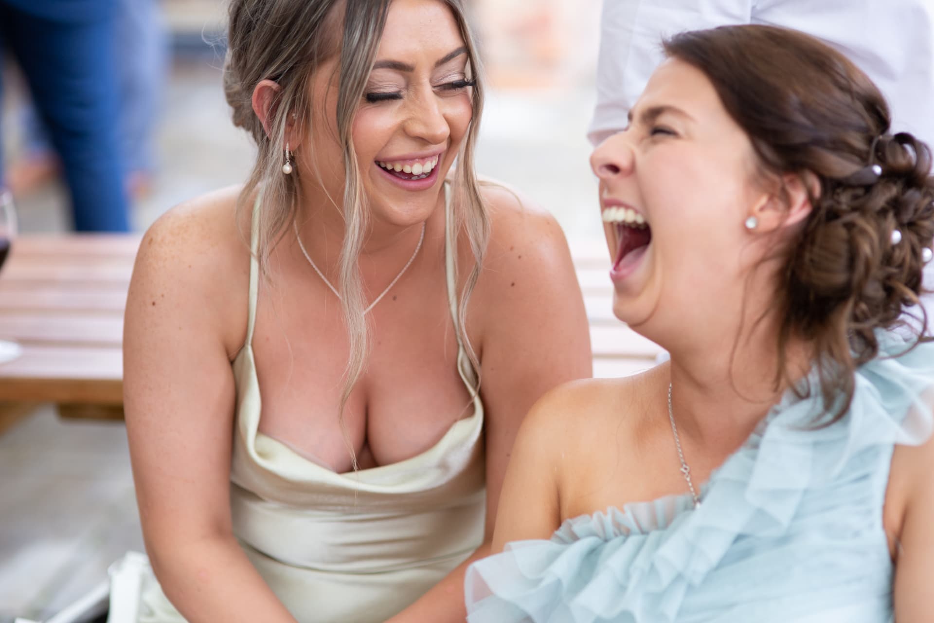 Two bridesmaids in fits of laughter at the reception