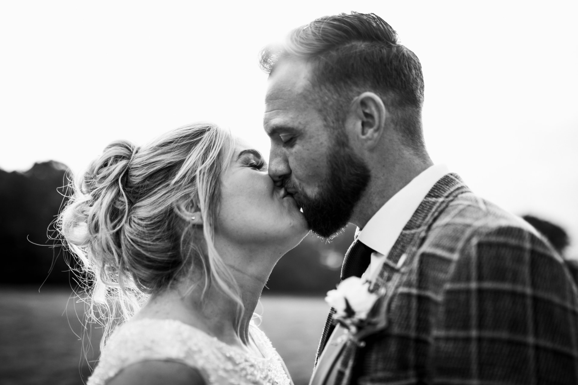Backlit black and white kiss between bride and groom