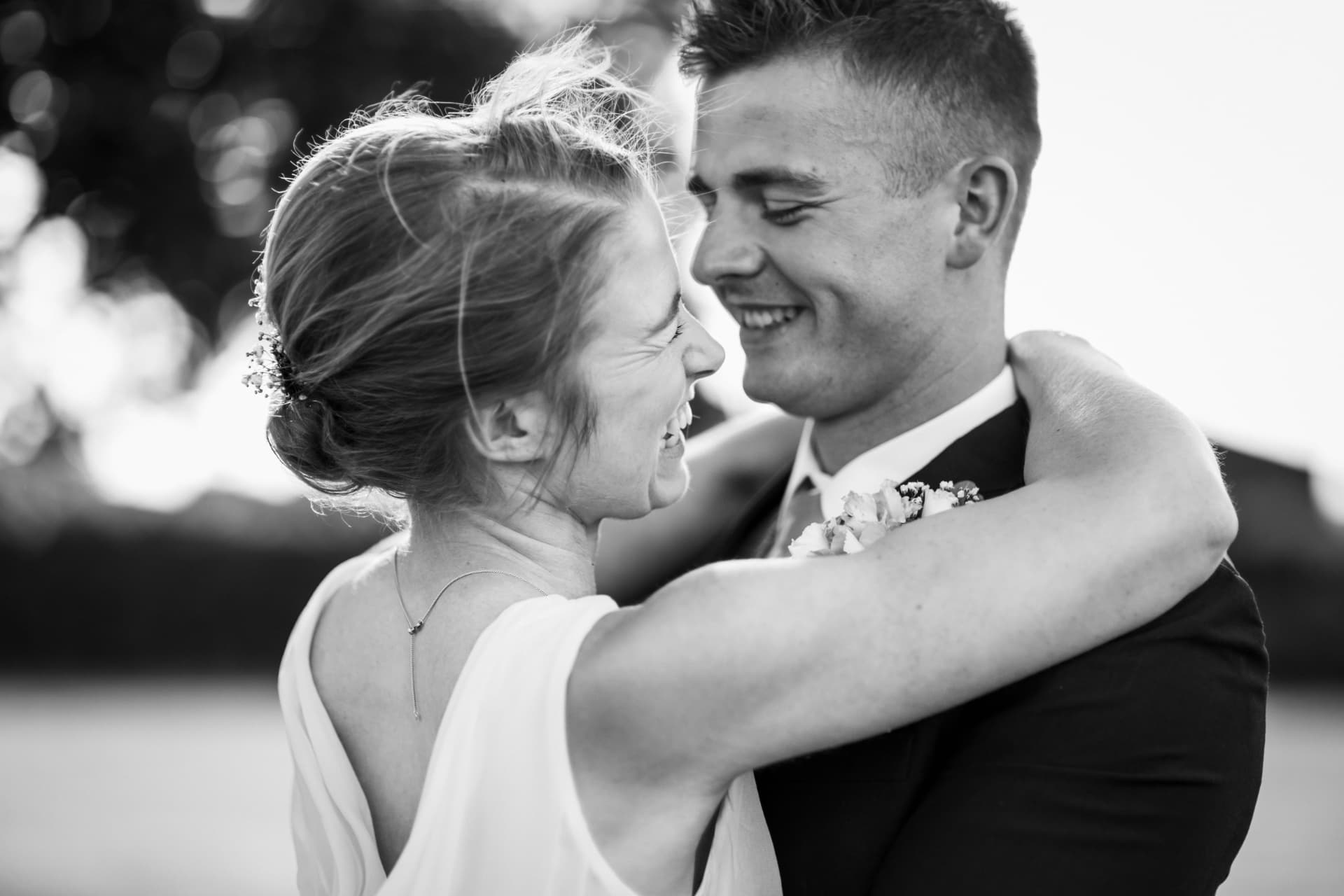 Bride and groom laughing in a close embrace, black and white