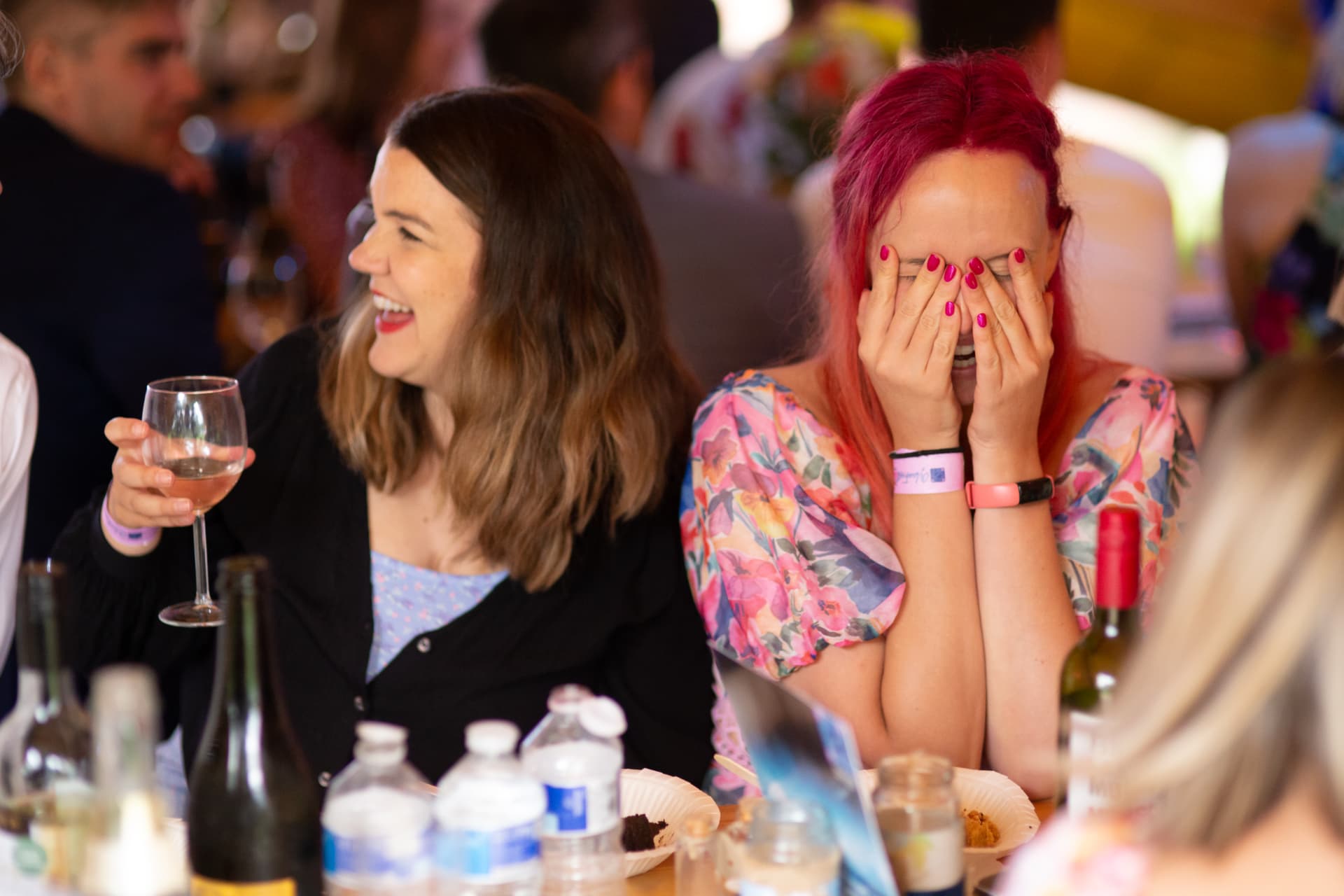 Pink-haired guest hiding her face laughing at the table